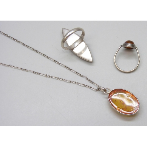 7082 - A silver amber set ring, a silver mounted amber pendant on chain, and a white metal amber ring