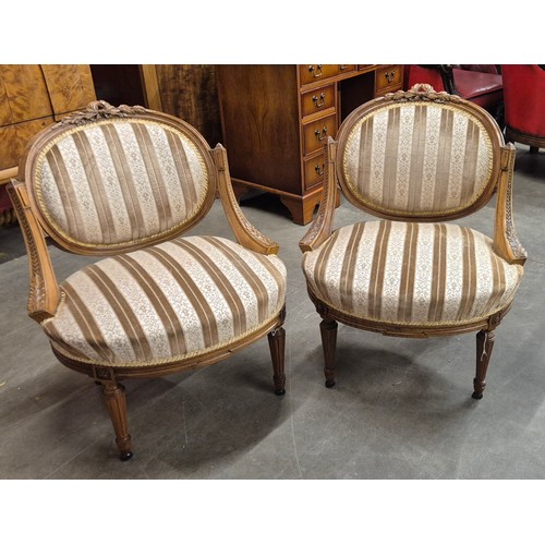 70 - A pair of French Louis XV style carved walnut and fabric upholstered fauteuil chairs