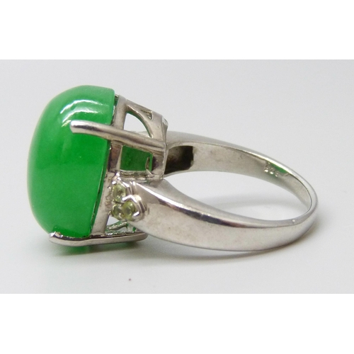 7104 - A silver ring set with an 11ct green jade central stone with peridot set shoulders, O