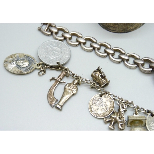 7133 - A white metal charm bracelet with a collection of silver and white metal charms, a silver napkin rin... 