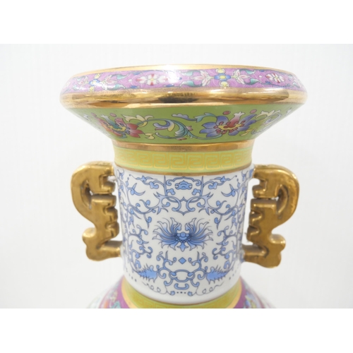 2180 - A large Chinese famille rose temple vase with panelled oriental scenes and gilt twin handles. With s... 