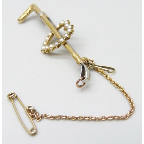 7057 - A 15ct gold and seed pearl brooch in the form of a riding crop, yellow metal safety chain, metal pin... 