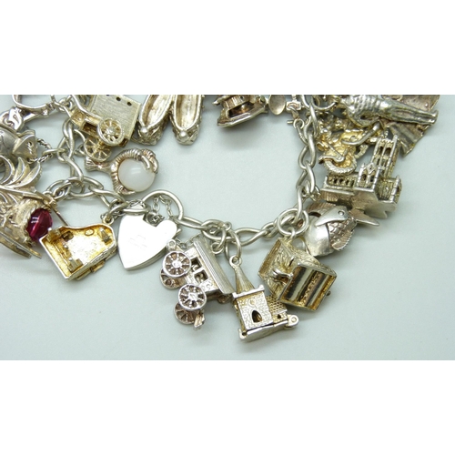 7103 - A silver charm bracelet with 26 silver and white metal charms, 103g