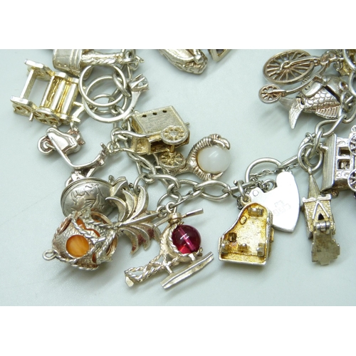 7103 - A silver charm bracelet with 26 silver and white metal charms, 103g