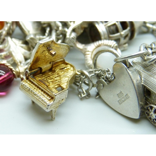 7103 - A silver charm bracelet with 26 silver and white metal charms, 103g