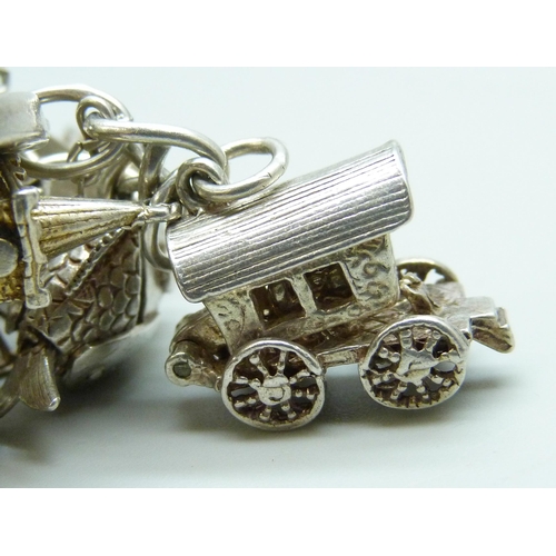 7103 - A silver charm bracelet with 26 silver and white metal charms, 103g