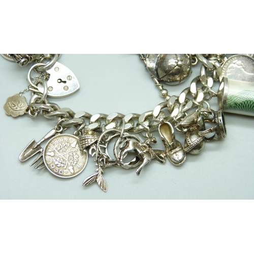 7104 - A silver charm bracelet with 27 silver and white metal charms, 109g