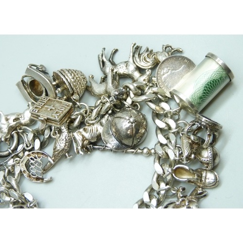 7104 - A silver charm bracelet with 27 silver and white metal charms, 109g