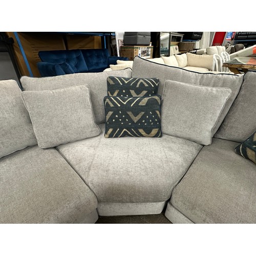 3206 - A stone grey upholstered three piece corner sofa with blue piping