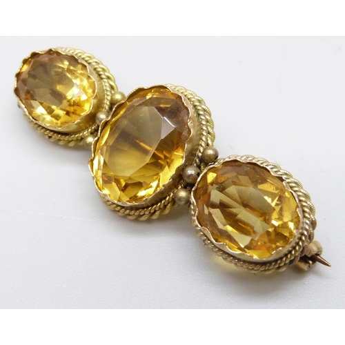 7020 - A 9ct gold three stone citrine brooch with rope design border, 8.1g, 4.3cm