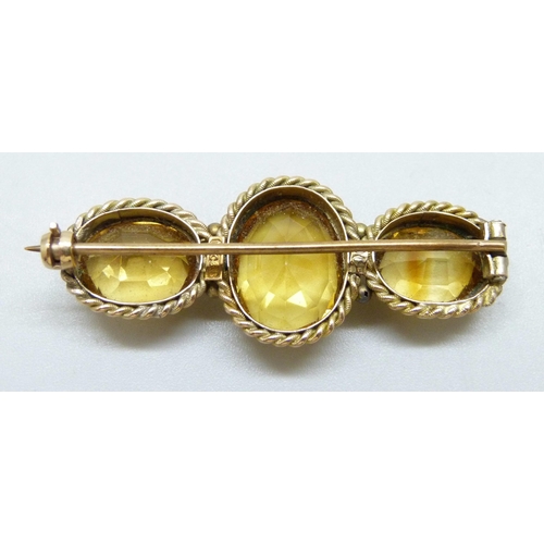 7020 - A 9ct gold three stone citrine brooch with rope design border, 8.1g, 4.3cm