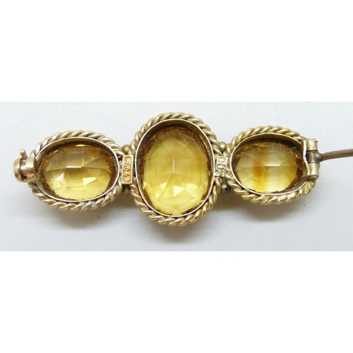 7020 - A 9ct gold three stone citrine brooch with rope design border, 8.1g, 4.3cm