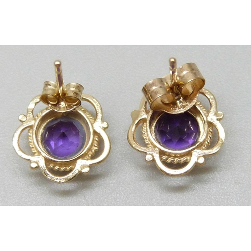 7039 - A pair of yellow metal amethyst stud earrings, unmatched butterflies, 1.1g