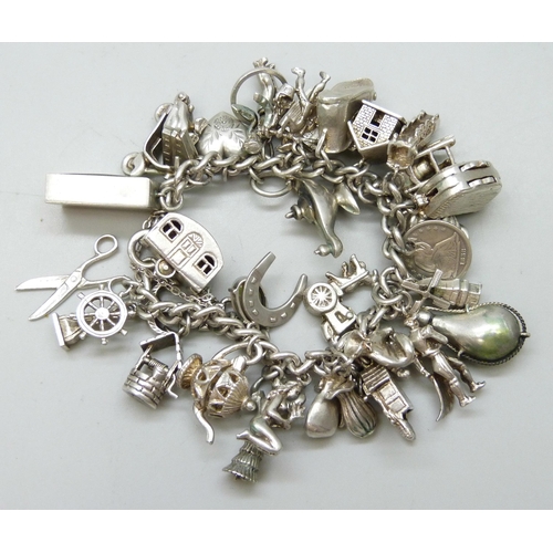 7090 - A heavy silver charm bracelet with 33 silver and white metal charms including a Georg Jensen 'Emerge... 