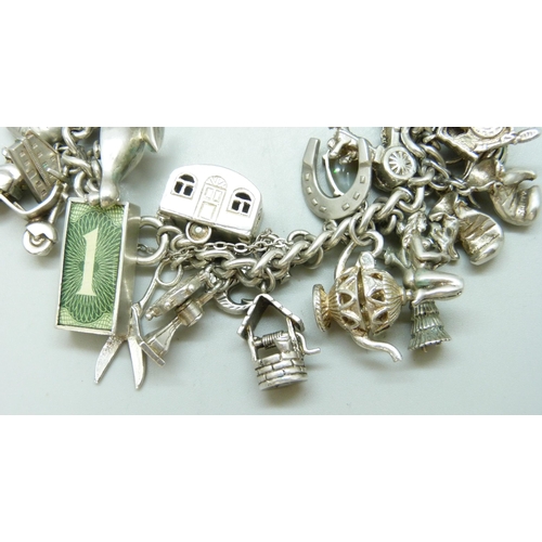 7090 - A heavy silver charm bracelet with 33 silver and white metal charms including a Georg Jensen 'Emerge... 