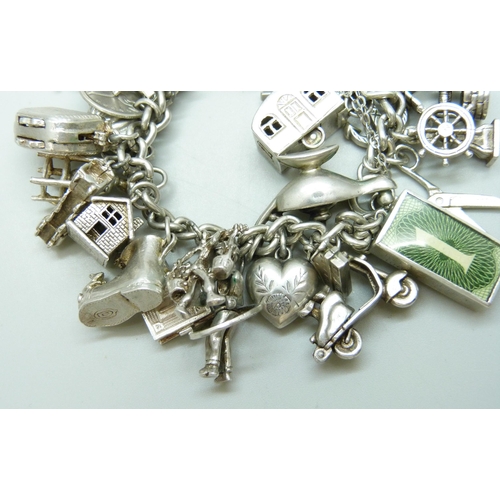 7090 - A heavy silver charm bracelet with 33 silver and white metal charms including a Georg Jensen 'Emerge... 