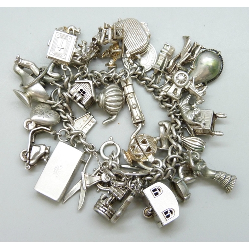 7090 - A heavy silver charm bracelet with 33 silver and white metal charms including a Georg Jensen 'Emerge... 