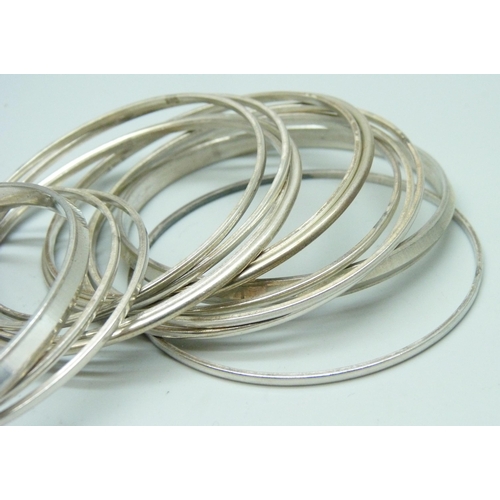 7102 - A white metal cuff bangle, four other white metal bangles, and thirteen stamped silver bangles, 130g... 