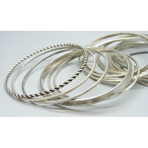 7102 - A white metal cuff bangle, four other white metal bangles, and thirteen stamped silver bangles, 130g... 