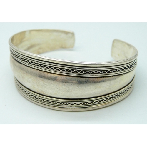 7102 - A white metal cuff bangle, four other white metal bangles, and thirteen stamped silver bangles, 130g... 