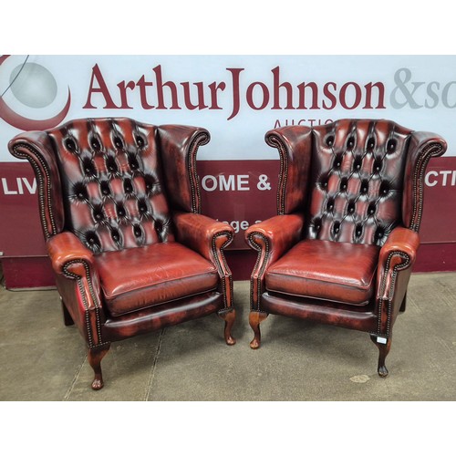 1 - A pair of oxblood red leather Chesterfield wingback armchairs