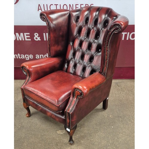 1 - A pair of oxblood red leather Chesterfield wingback armchairs