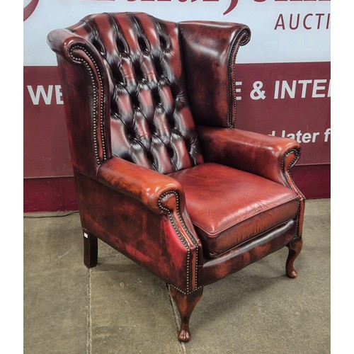 1 - A pair of oxblood red leather Chesterfield wingback armchairs