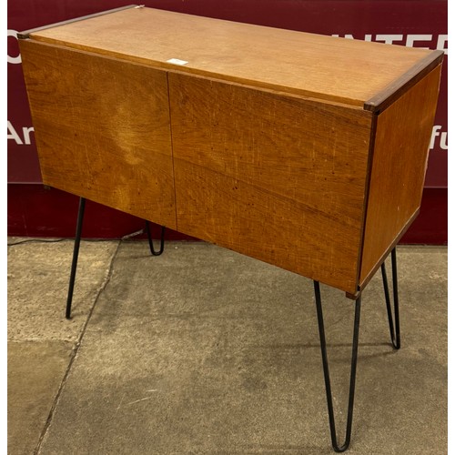 67 - A teak two door cabinet, on black metal hairpin legs