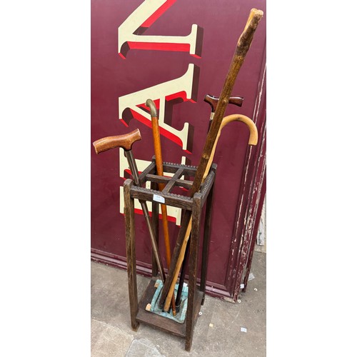 329 - An early 20th Century oak stickstand and a collection of walking sticks