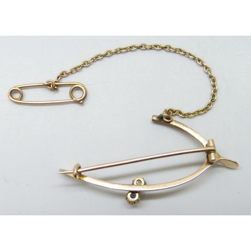 7008 - A yellow metal wishbone style brooch set with a diamond and a sapphire, 4.2g, 4.4cm