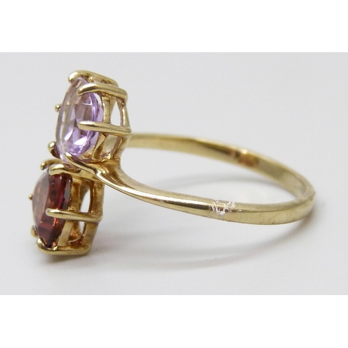 7048 - A 9ct gold crossover ring set with a garnet and an amethyst, 2.3g, P