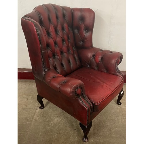 223 - An oxblood red leather Chesterfield wingback armchair