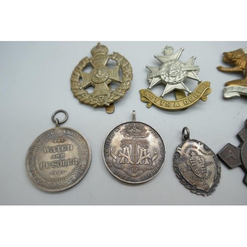 2178 - A collection of regimental cap badges, Queen Victoria medallions, etc.
