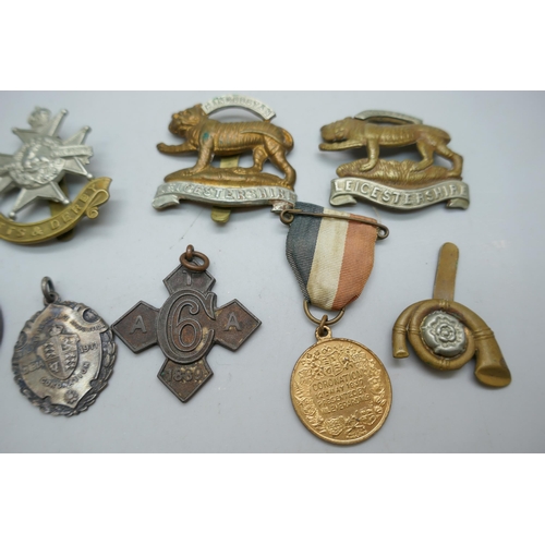 2178 - A collection of regimental cap badges, Queen Victoria medallions, etc.