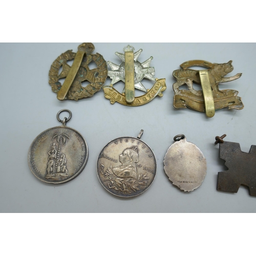2178 - A collection of regimental cap badges, Queen Victoria medallions, etc.