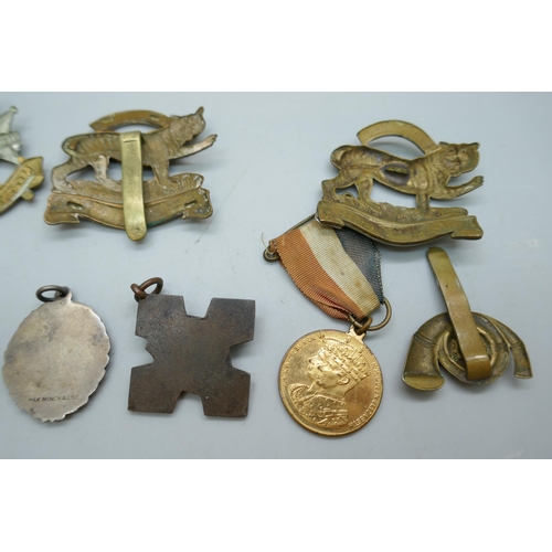 2178 - A collection of regimental cap badges, Queen Victoria medallions, etc.