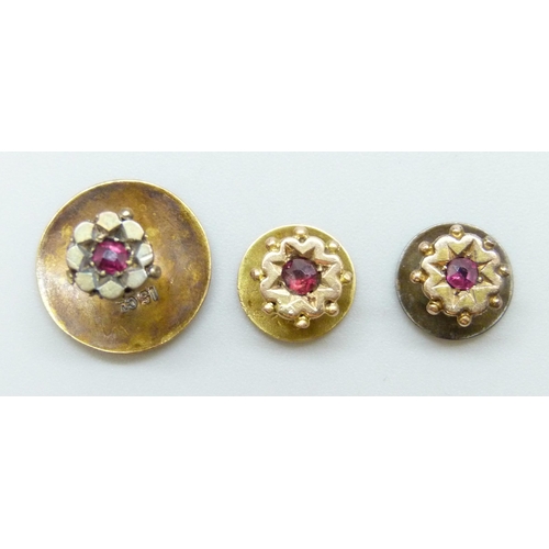 7011 - A set of three Victorian 15ct gold shirt studs set with rubies, with an associated box, 3g