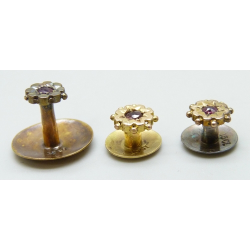 7011 - A set of three Victorian 15ct gold shirt studs set with rubies, with an associated box, 3g