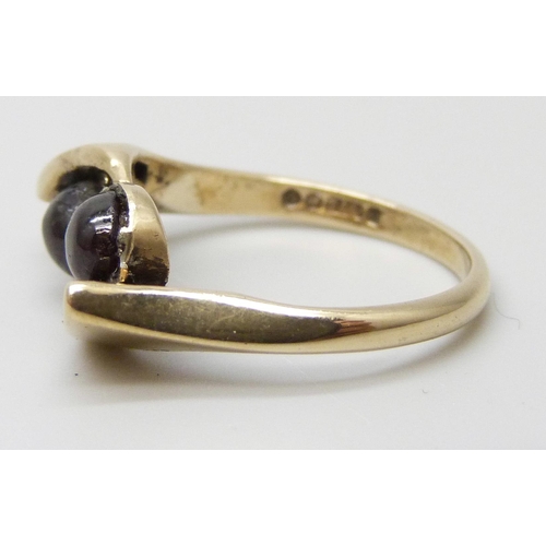 7051 - A 9ct yellow gold ring set with two garnet cabochons, 3.3g, L
