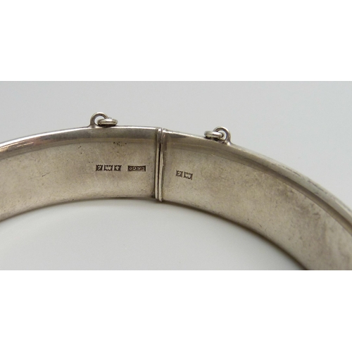 7043 - A hallmarked engraved silver bangle, 23g, 6 x 5cm