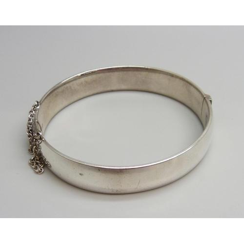 7043 - A hallmarked engraved silver bangle, 23g, 6 x 5cm