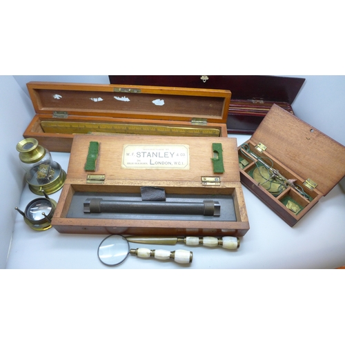 2044 - A Stanley rolling rule, boxed, two other boxes with wooden rulers, a cased set of balance scales wit... 