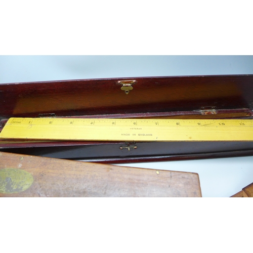 2044 - A Stanley rolling rule, boxed, two other boxes with wooden rulers, a cased set of balance scales wit... 