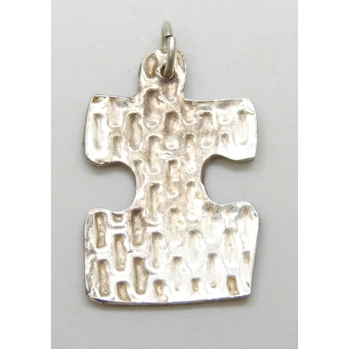 7061 - A white metal puzzle piece necklace pendant, tests as silver, 3.4cm including bail