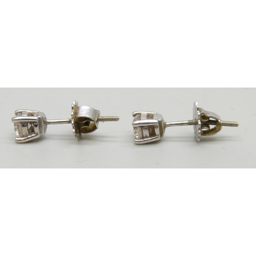 7267 - A pair of white metal diamond stud earrings, the screw back fasteners marked 9 carat gold, 1g total