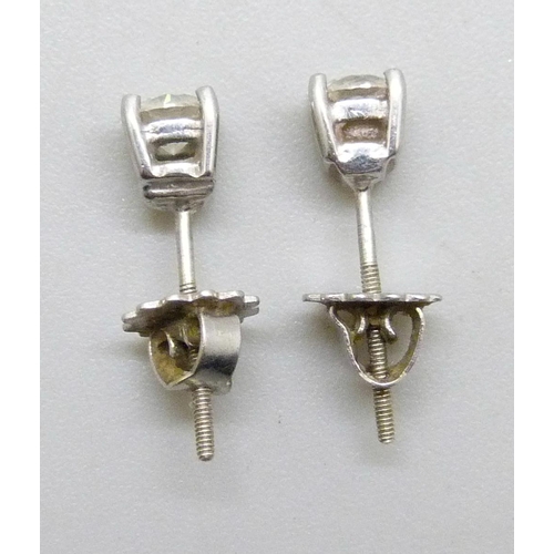 7267 - A pair of white metal diamond stud earrings, the screw back fasteners marked 9 carat gold, 1g total