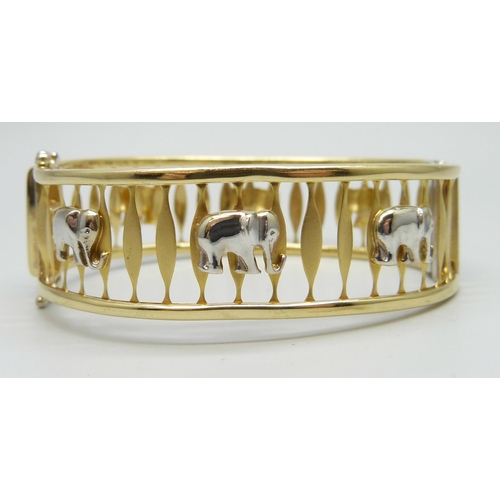 7004 - A two tone 14ct gold bangle with elephant design, marked Magar 585, 24.1g, 6 x 5cm, 1.9cm wide