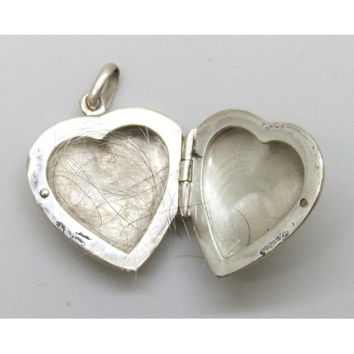 7140 - A silver ring, R, a white metal heart locket, and a silver cross pendant, 12g