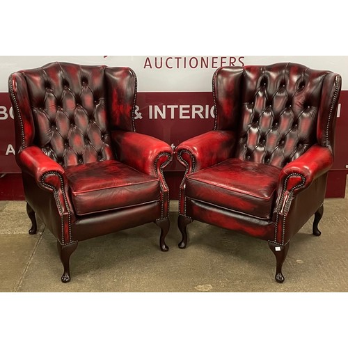 64 - A pair of Queen Anne style oxblood red leather wingback armchairs