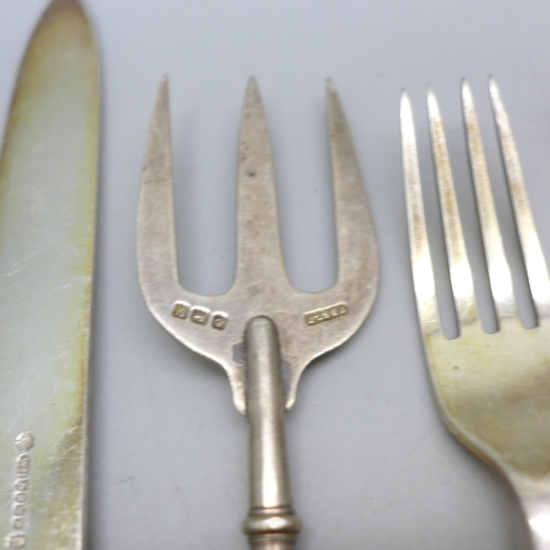 7396 - A collection of silver plated knives and forks with mother of pearl handles, a silver fork example, ... 